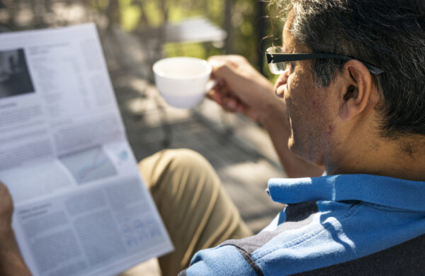 Man relaxing while reading a newspaper and drinking coffee Man relaxing while reading a newspaper and drinking coffee